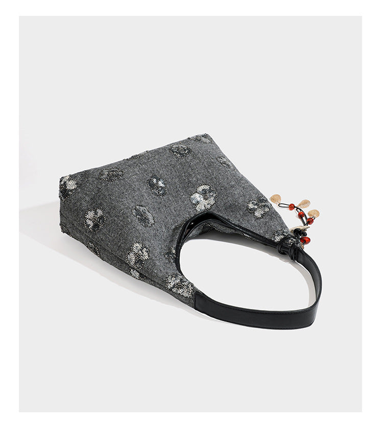 Lässig fallende, trapezförmige Schulter-Tote in Anthrazitgrau mit floralen Paillettenmotiven in Silber, Riemen in Lederoptik und herabhängendem Perlenbesatz