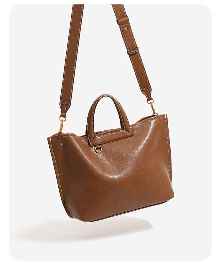 Structured cognac brown leather-look tote bag with fold-ear side panels, top handles, gold-tone hardware, and detachable