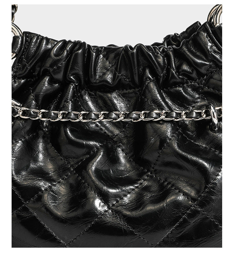 Glossy diamond-quilted drawstring bucket bag with silver chain shoulder strap and medallion charm, detail view 18