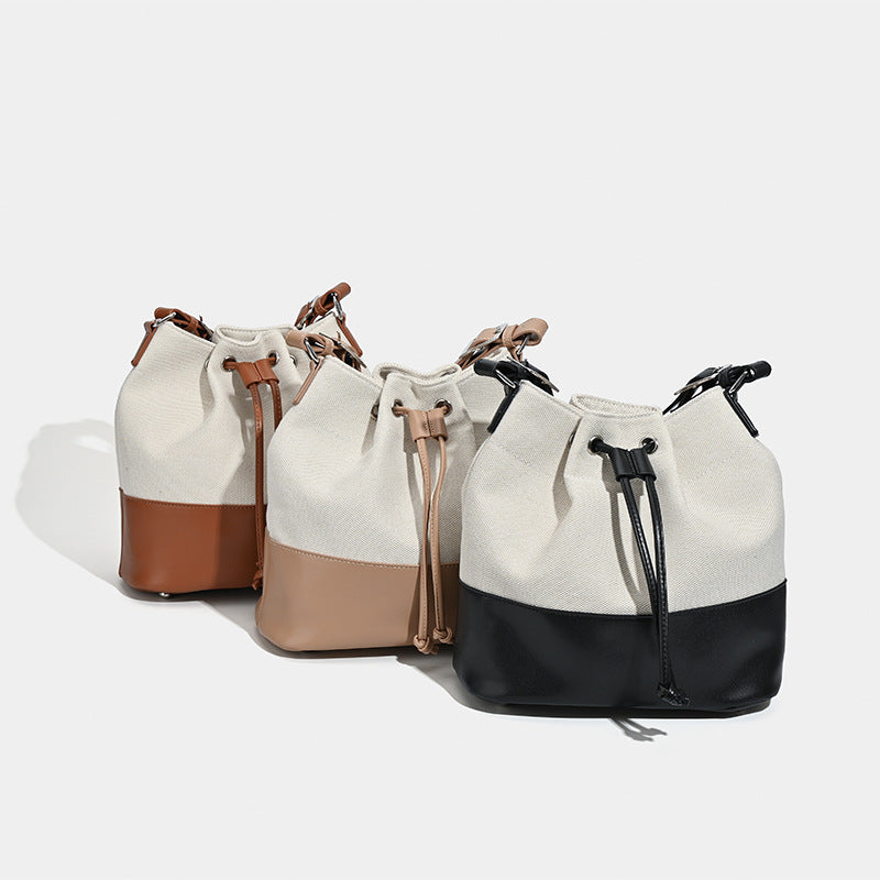 Cream canvas drawstring bucket bag with contrasting leather-look lower panel and adjustable shoulder strap, detail view 2