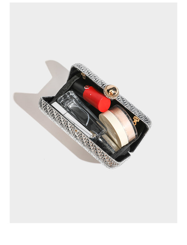 Small structured metallic woven-texture box clutch bag with jeweled kiss-lock dome clasp and slim gold chain strap, detail