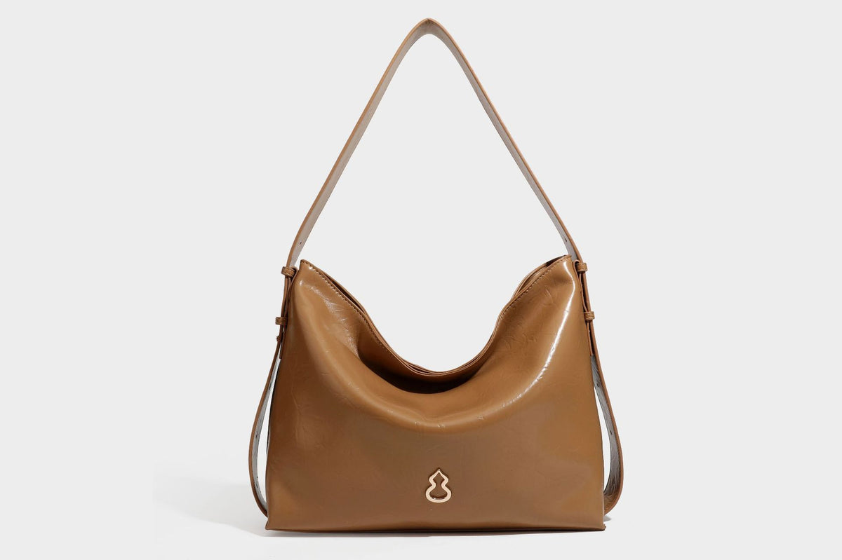 Lässig fallende Hobo-Schultertasche mit offenem Oberteil aus glänzender, karamellbrauner Lederoptik, mit Logo-Beschlägen in Goldoptik und langem, verstellbarem
