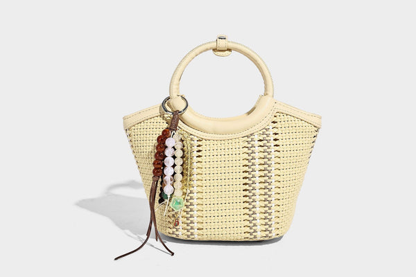 Kleine strukturierte Beuteltasche aus geflochtenem Material mit rundem Tragegriff in Lederoptik, silberfarbenen Beschlägen und perlenbesetztem Quastenanhänger, Detail