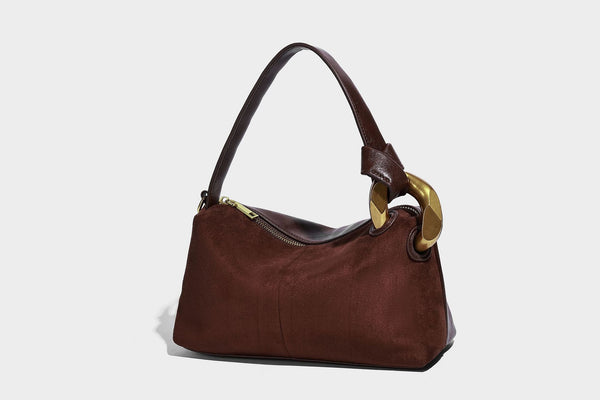 Kompakte Boston-Schultertasche in warmem Braun in Wildlederoptik mit glattem dunkelbraunem Besatz, übergroßen goldfarbenen Ringelementen und Reißverschluss oben
