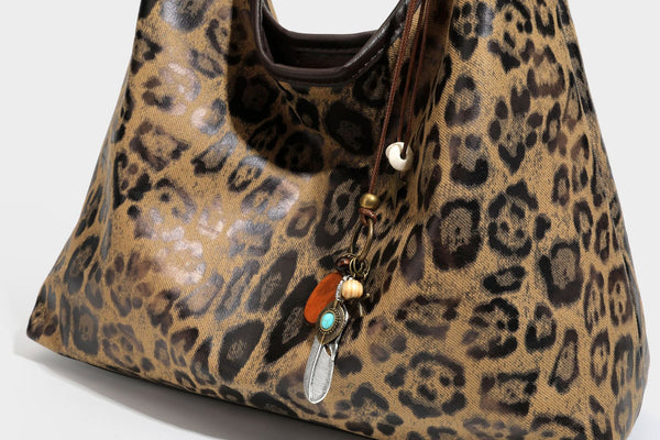 Weich fallende Hobo-Tote-Bag mit Leopardenmuster in Beige und Braun, dunkelbraunem Riemen in Lederoptik und herabhängenden Perlenanhänger-Beschlägen