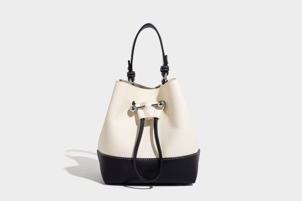 Small two-tone pebbled drawstring bucket bag with tan contrast base, metal toggle hardware, short top handle, and detachable