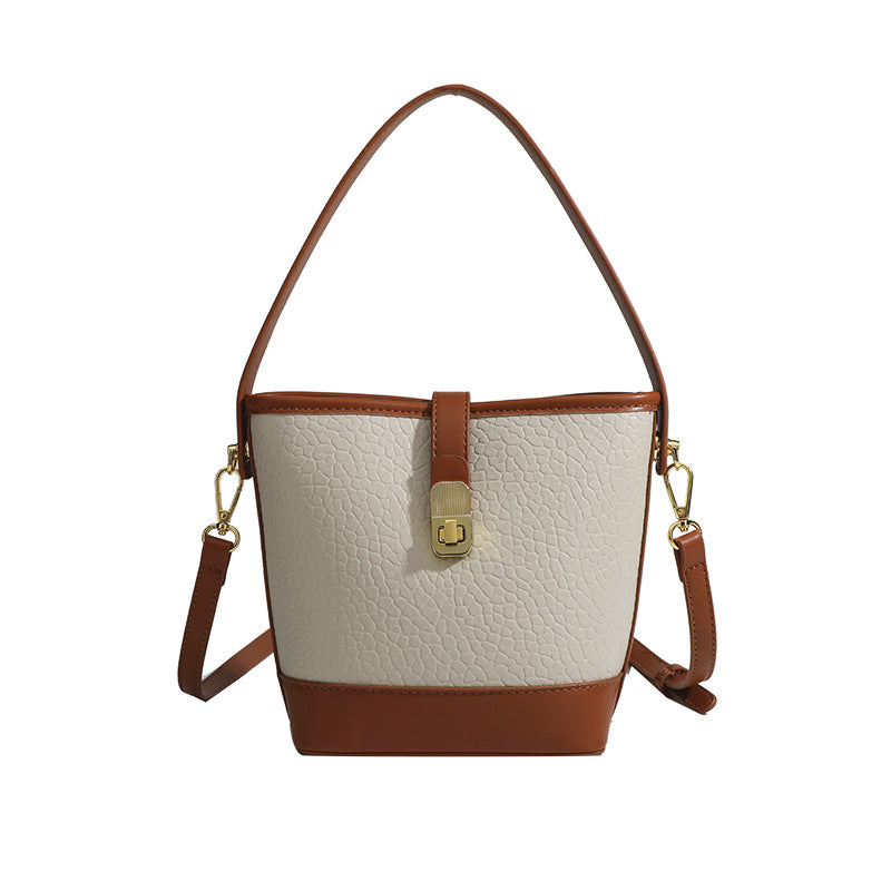 Formstabile zweifarbige Bucket Bag aus genarbtem Material mit goldfarbenem Drehverschluss und cognacfarbenem Besatz in Lederoptik, Detailansicht 5