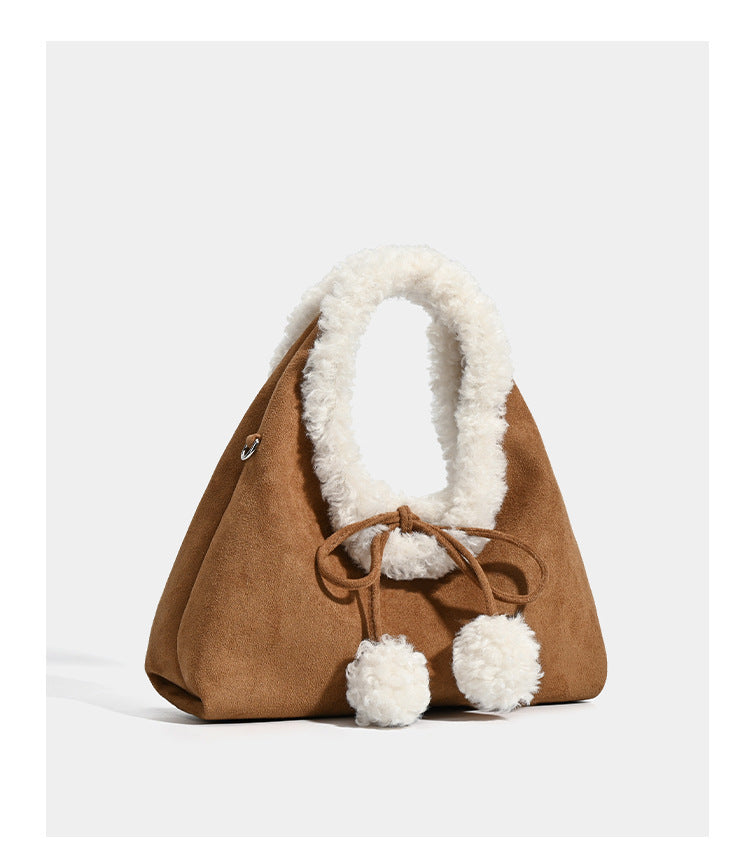 Trapezförmige Tasche in Karamellbraun mit Wildlederoptik, ovalem Henkel aus weißem Kunstfell, Kordelverschluss mit Pompons und abnehmbarem Schulterriemen