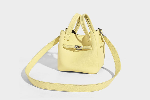 Small structured pebbled bucket tote bag with dual top handles, silver turn-lock front pocket, and detachable shoulder strap