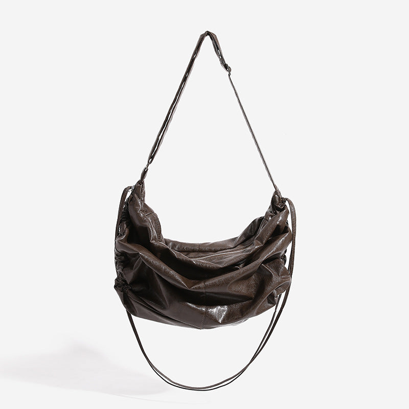 Oversized slouchy hobo shoulder bag with glossy crinkled leather-look finish, drawstring gathered sides, and silver-tone