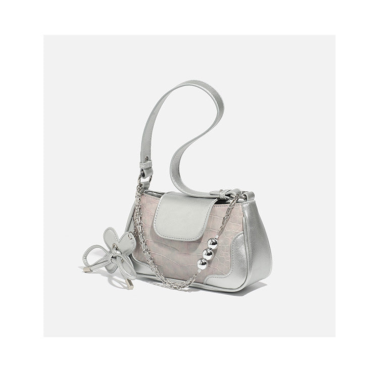 Compact silver flap shoulder bag with pale-pink crocodile-embossed panel, chain bead handle, bow charm, and adjustable