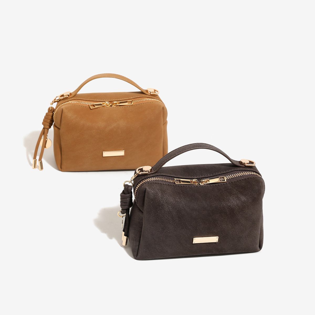 Compact boxy mini handbag with matte pebbled finish, dual top zipper, short top handle, side tassel charm, and gold-tone