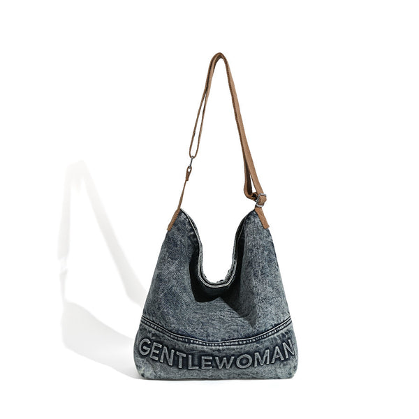 Washed blue denim slouchy open-top shoulder tote bag with tan leather-look adjustable crossbody strap and embroidered, detail