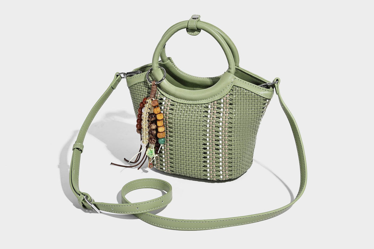 Kleine strukturierte Beuteltasche aus geflochtenem Material mit rundem Tragegriff in Lederoptik, silberfarbenen Beschlägen und perlenbesetztem Quastenanhänger, Detail