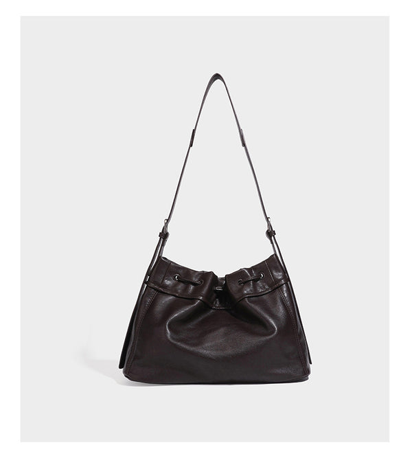 Slouchy drawstring bucket bag in dark brown leather-look finish with long adjustable shoulder strap and gathered tie closure