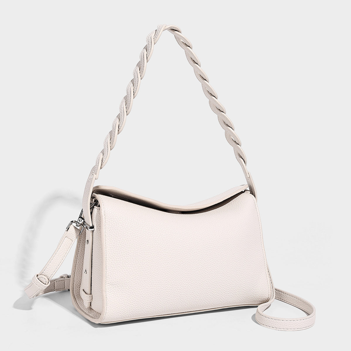Small structured pebbled-finish shoulder bag with braided top handle, detachable crossbody strap, floral tassel charm, and