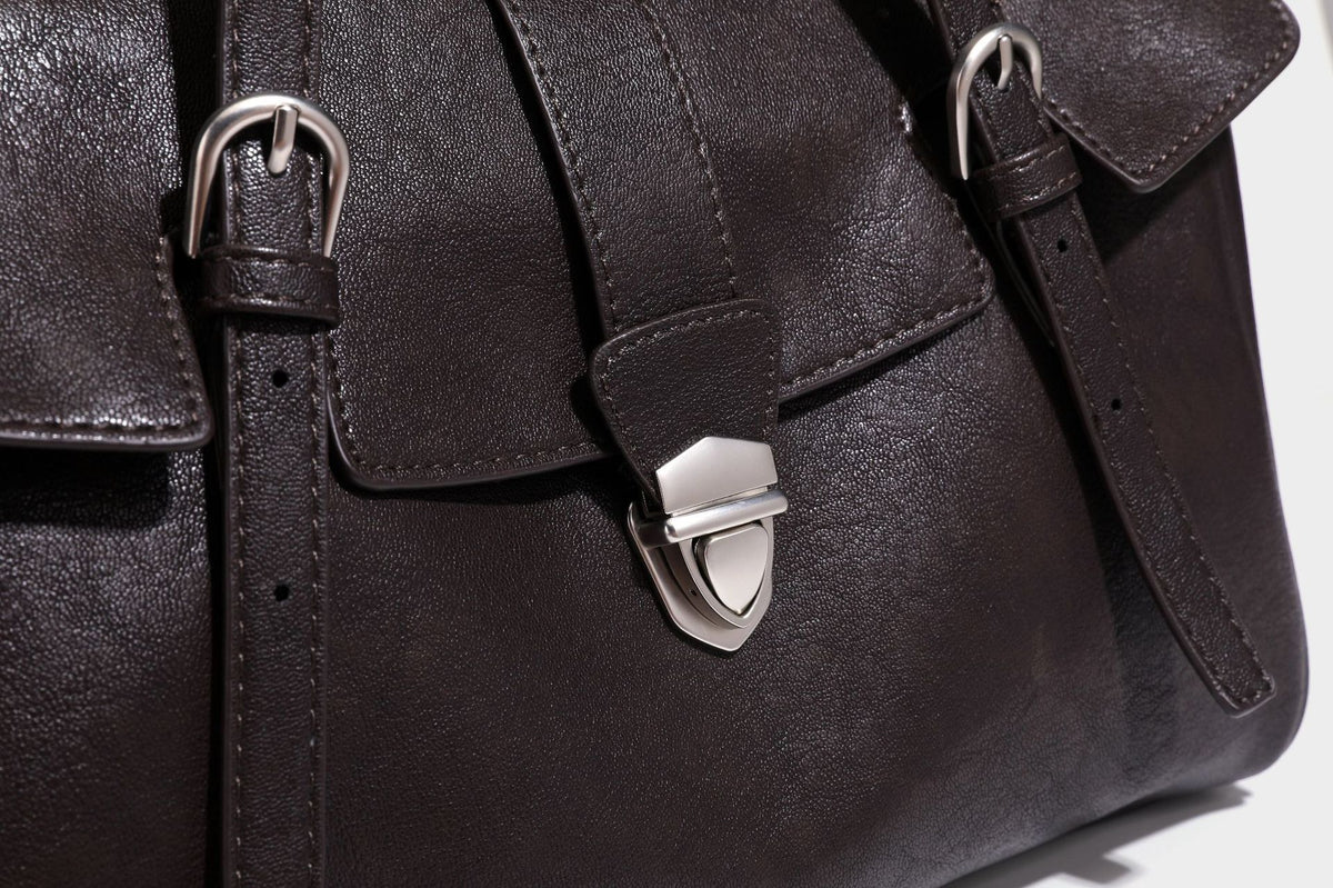 Large structured vintage-style tote bag with flap-front turn-lock closure, twin buckle straps, and double shoulder handles