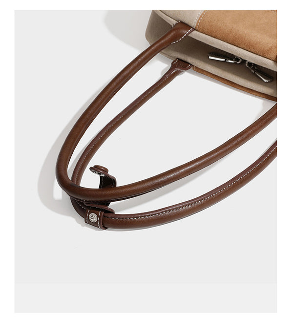 Boxy patchwork suede-look shoulder tote in tan, beige, rust, and brown panels with double brown straps and hanging doll