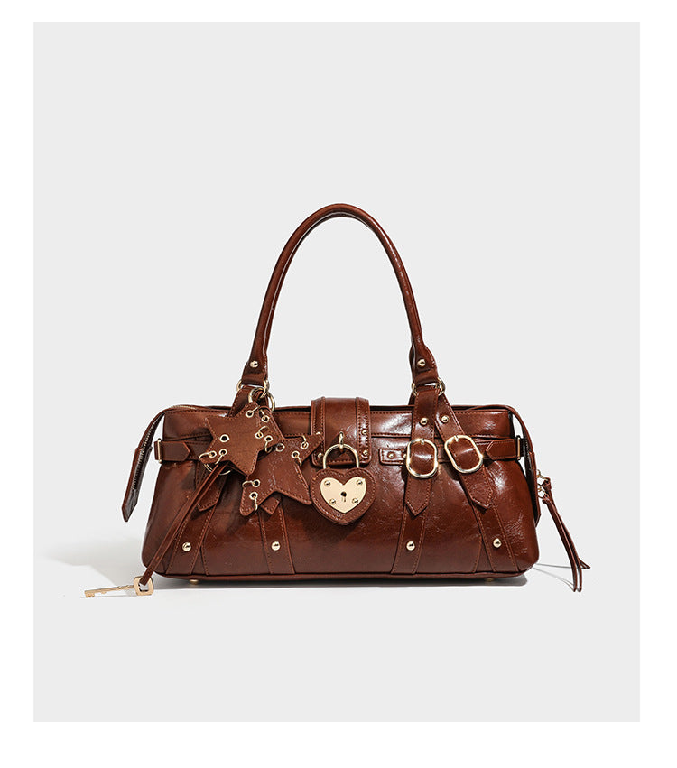 Dark brown glossy crinkled leather-look barrel bag with gold heart lock, dome studs, star charm, dual top handles and, detail