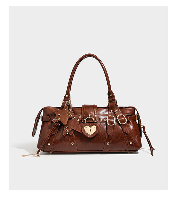 Dark brown glossy crinkled leather-look barrel bag with gold heart lock, dome studs, star charm, dual top handles and, detail