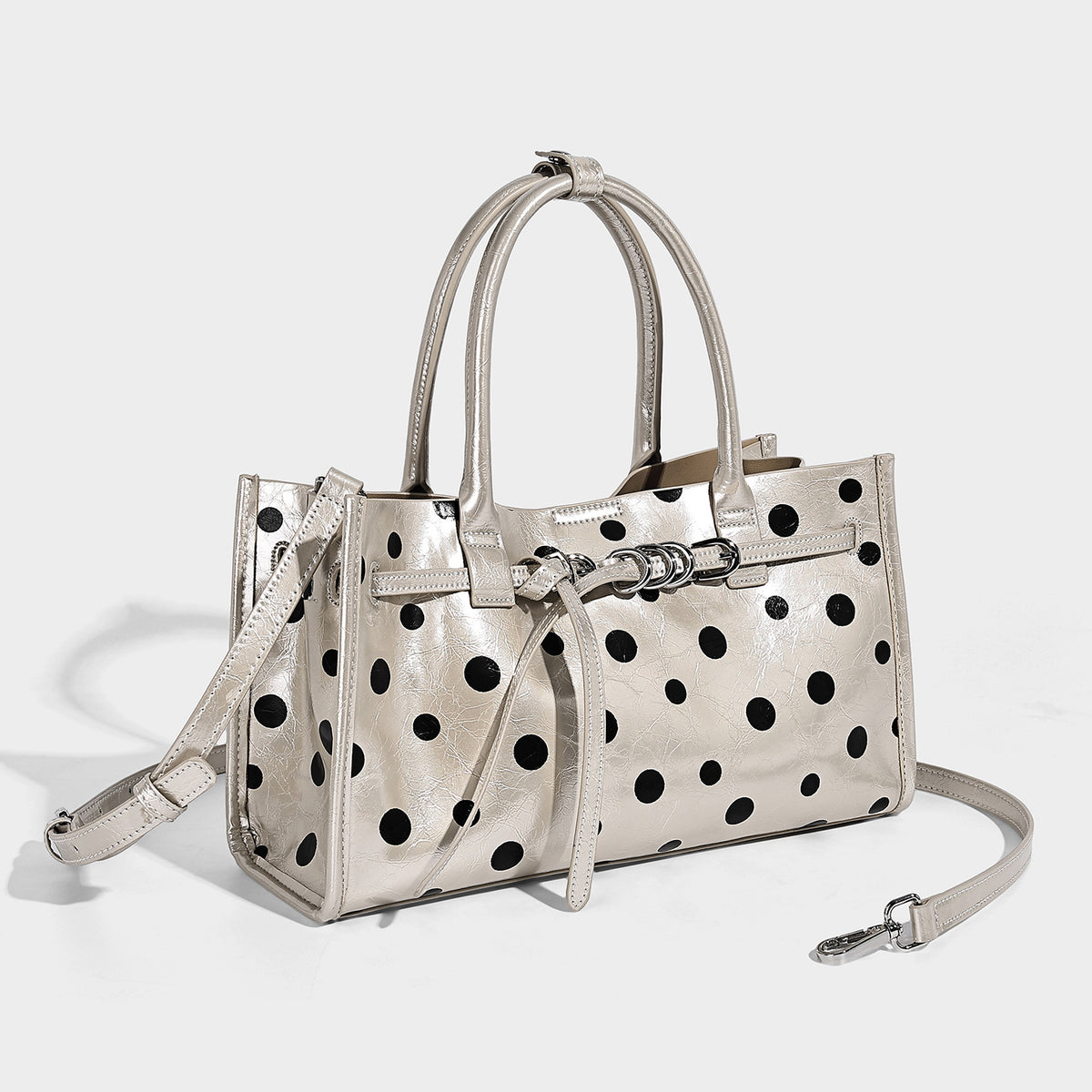 Structured glossy polka-dot tote bag with double top handles and front buckle hardware, detail view 3