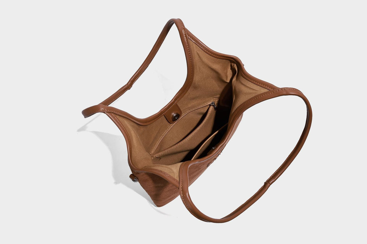 Tote-Bag in warmem Braun mit matter Wildlederoptik, langen Tragegriffen, geprägtem Logo, silberfarbenen Beschlägen und passendem, Detail