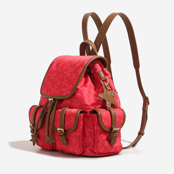Red floral-print backpack handbag with brown leather-look trim, dual front buckle pockets, star charms, and gold-tone, detail