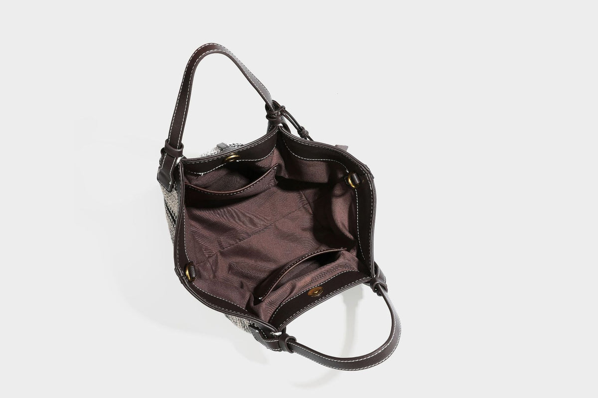 Schwarz-weiße gewebte Trapez-Tote-Bag mit dunklem Lederimitat-Besatz, weißen Kontrastnähten und zwei Henkeln, Detailansicht