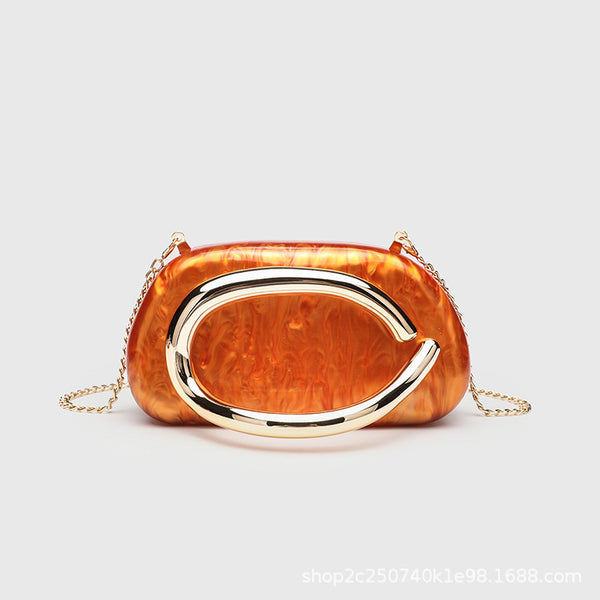 Kleine rechteckige Crossbody-Clutch mit abgerundeten Ecken, oversized poliertem C-förmigem Goldgriff und schmalem Goldkettenriemen, Detailansicht