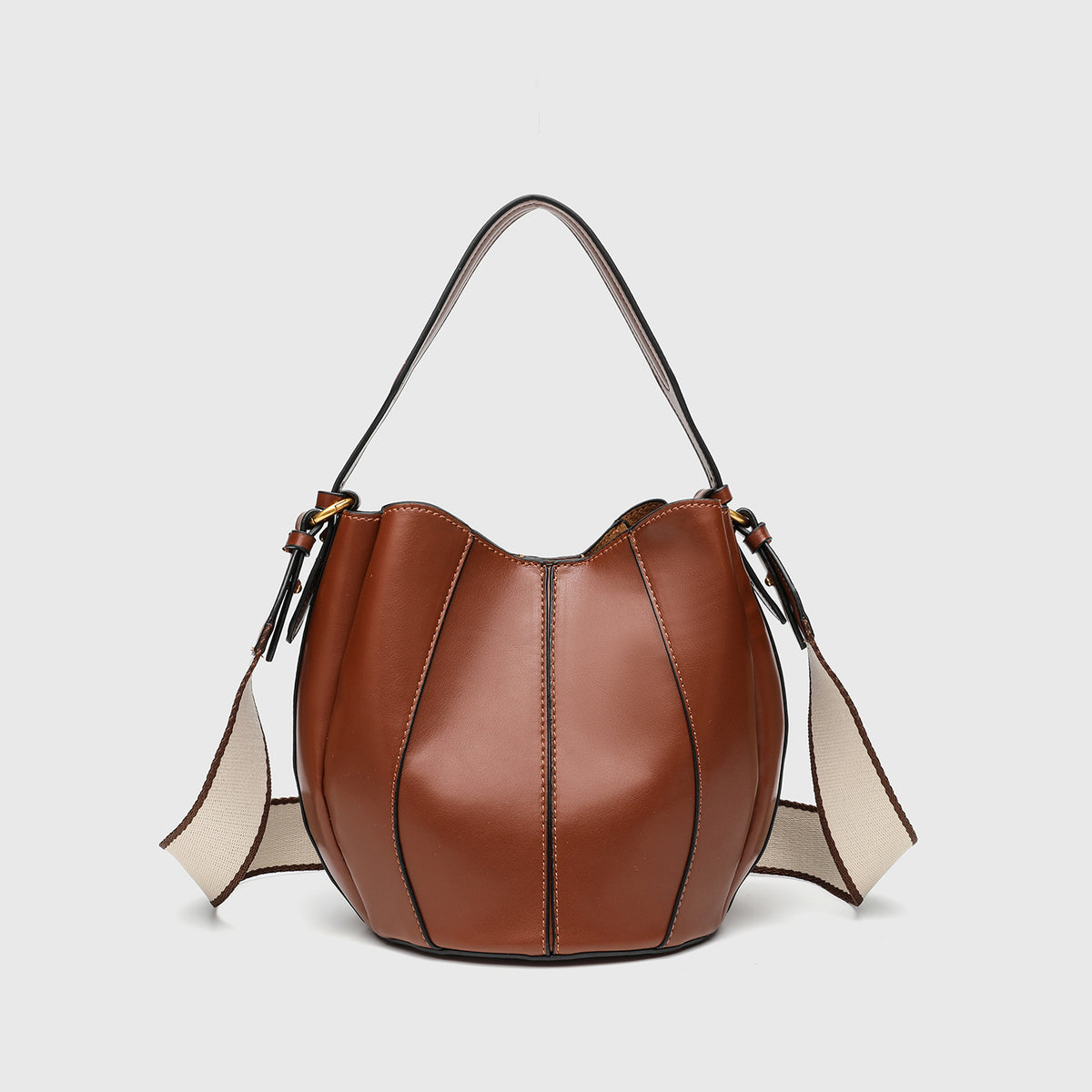 Smooth leather-look paneled bucket bag in brown with wide woven shoulder strap, gold-tone ring hardware, and detachable zip