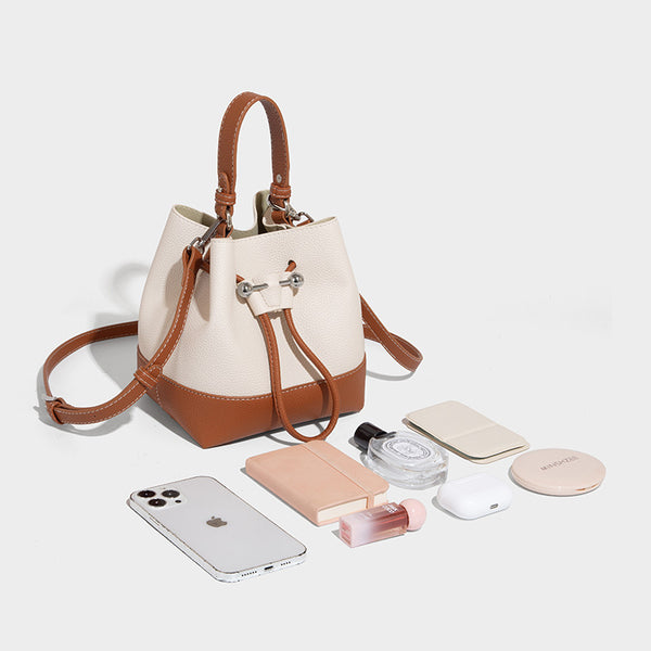 Small two-tone pebbled drawstring bucket bag with tan contrast base, metal toggle hardware, short top handle, and detachable