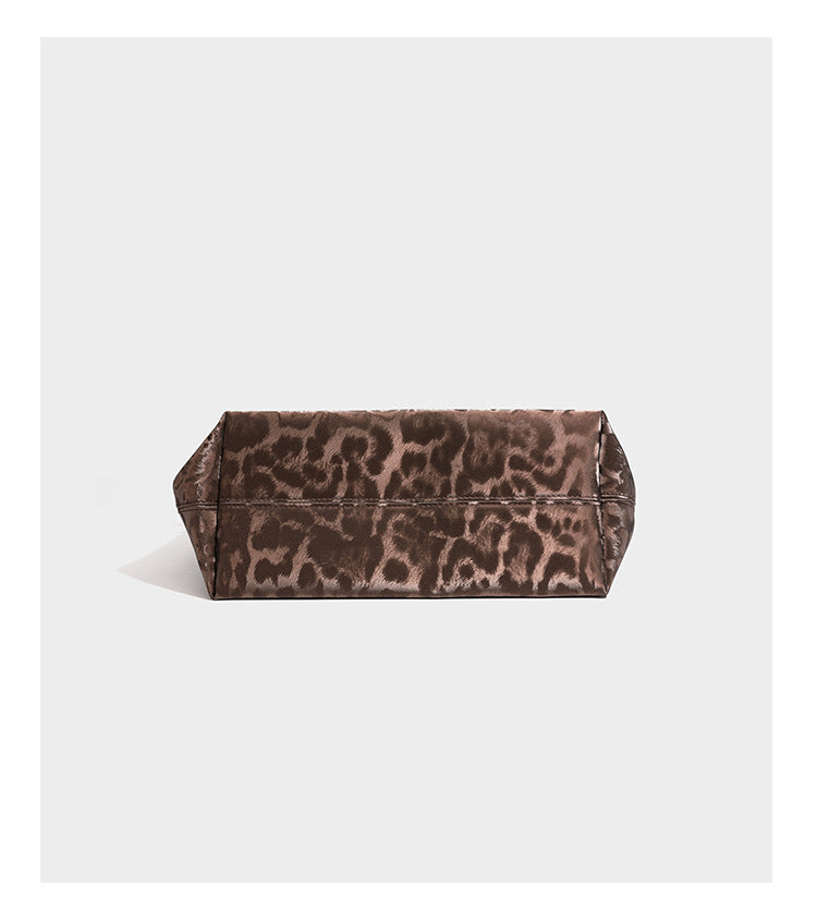 Glossy leopard-print tote bag with leather-look dark trim, dual top handles, detachable shoulder strap, and attached front