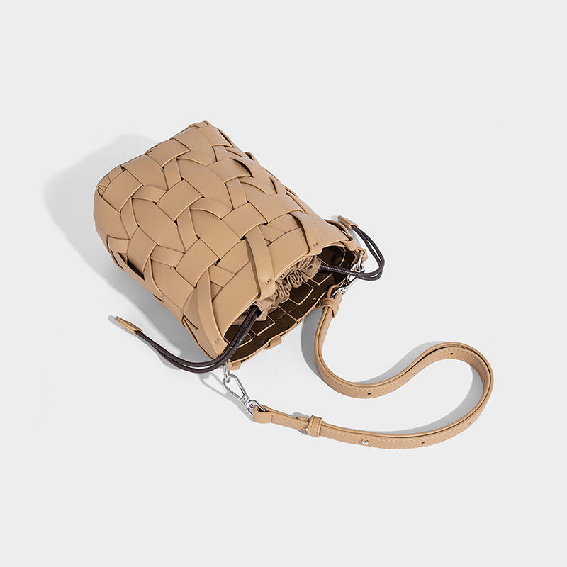 Small woven leather-look bucket bag with interlaced strip exterior, drawstring closure, and adjustable crossbody strap