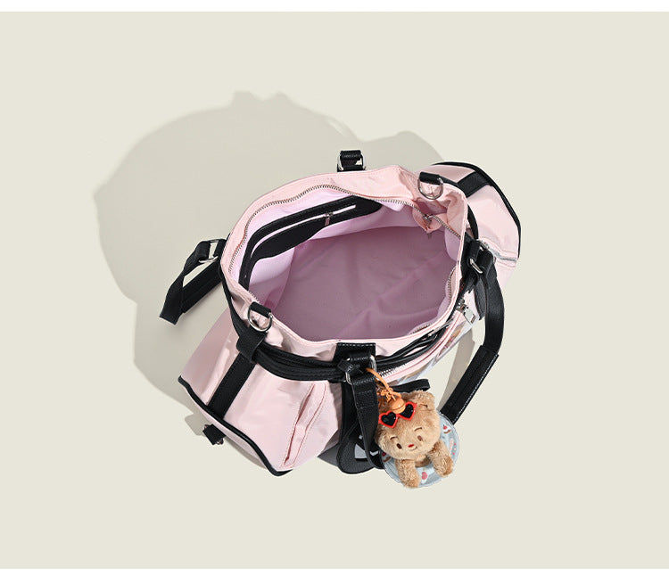 Pale pink nylon tote bag with black leather-look trim, double top handles, side zip pocket, and detachable crossbody strap