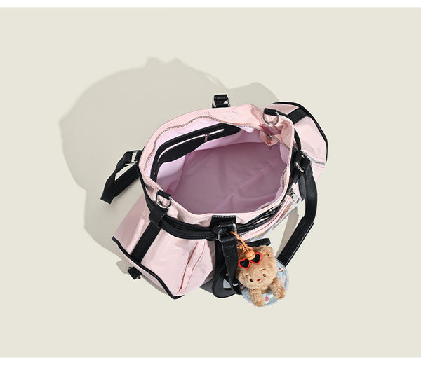 Pale pink nylon tote bag with black leather-look trim, double top handles, side zip pocket, and detachable crossbody strap