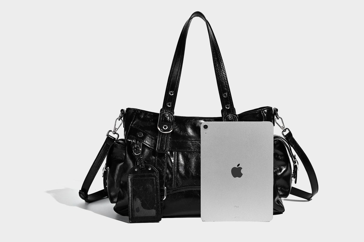 Glossy structured black tote shoulder bag with silver buckle hardware, zip pockets, dual top handles, and detachable, detail