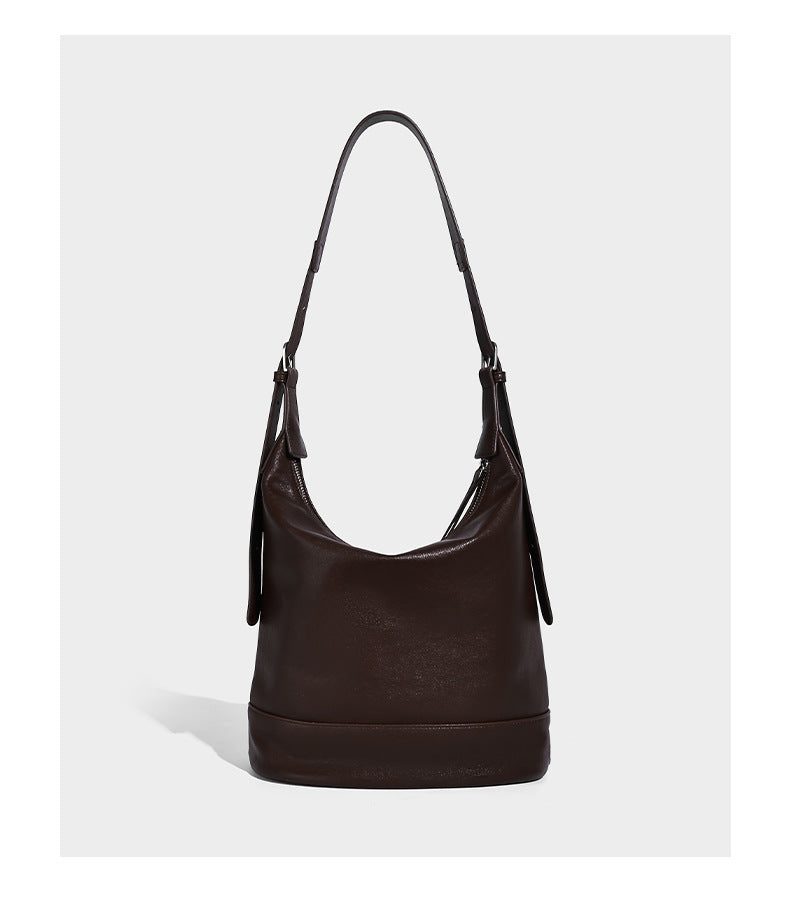 Slouchy bucket hobo shoulder bag in dark brown with glossy leather-look finish, top zip closure, and long adjustable, detail