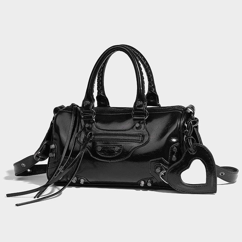 Glossy studded mini satchel bag with braided top handles, front zip pocket, heart charm, and detachable crossbody strap