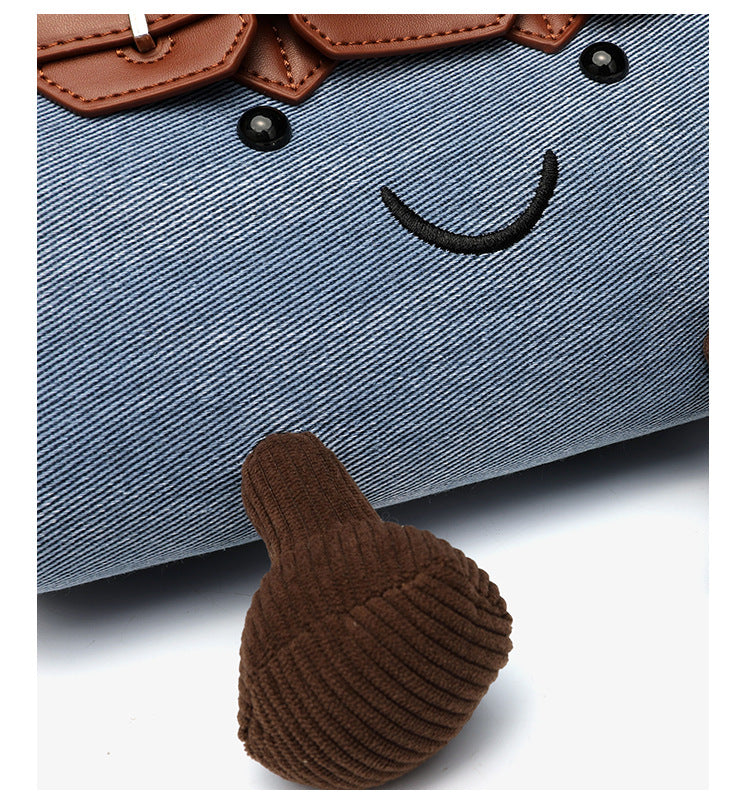 Small structured trapezoid satchel bag with smiling face motif, pom-pom accents, brown leather-look trim, silver-tone, detail
