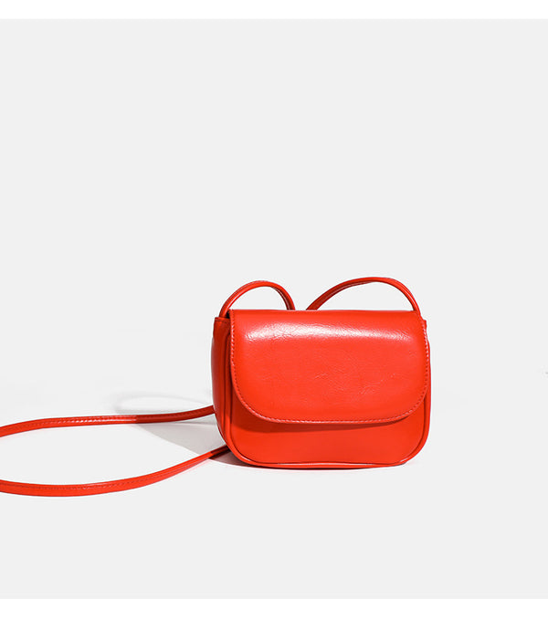 Compact rounded rectangular flap crossbody bag with glossy leather-look finish and long shoulder strap, detail view 10