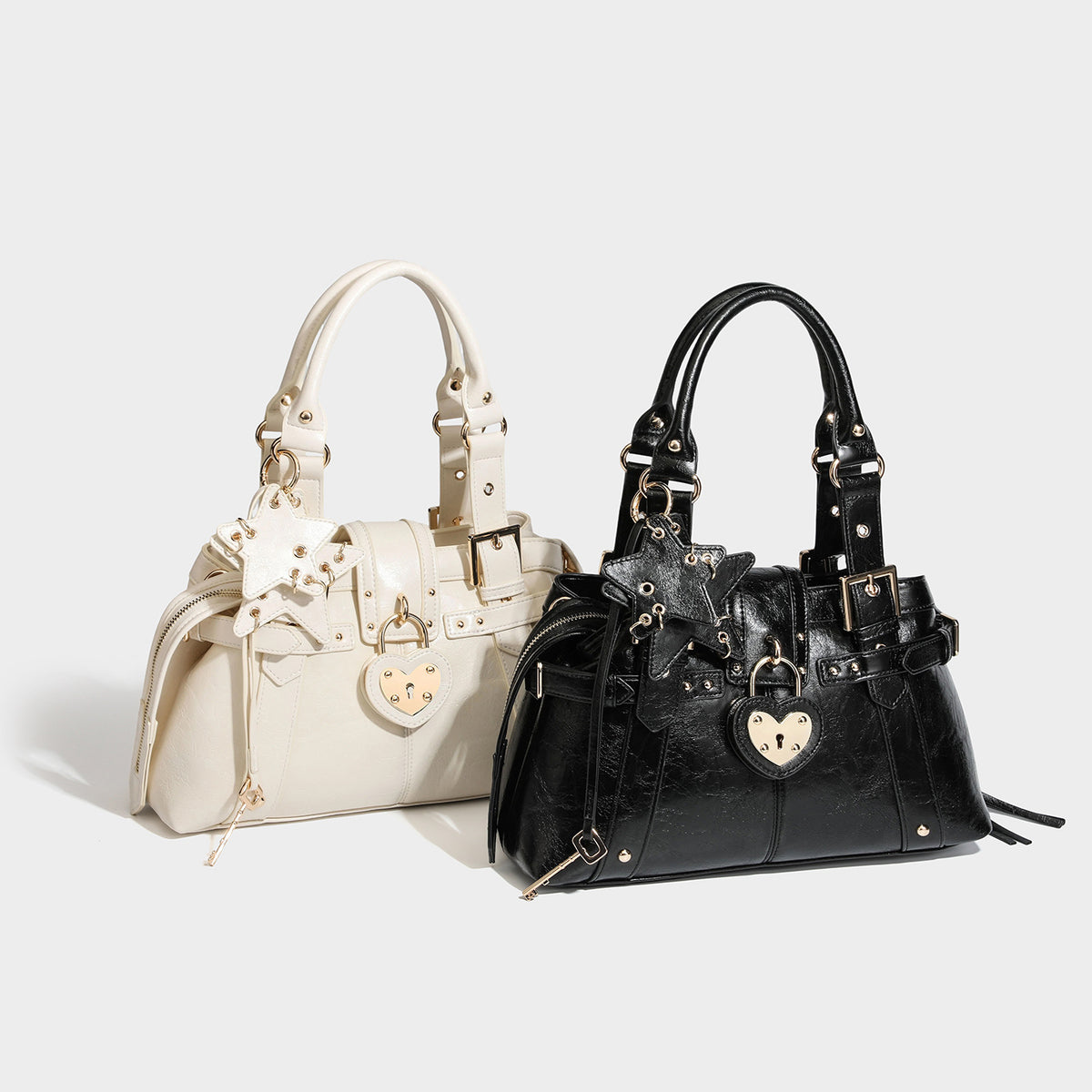 Structured leather-look satchel bag with heart padlock charm, star charm, gold-tone buckle hardware, dual top handles, and