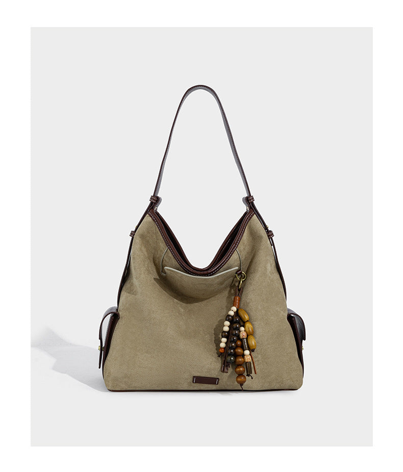 Lässig fallende Hobo-Schultertasche in Khaki aus mattem Material in Wildlederoptik mit dunkelbraunem Besatz in Lederoptik, Quastenanhänger mit Perlen und seitlicher Klappe, Detailansicht