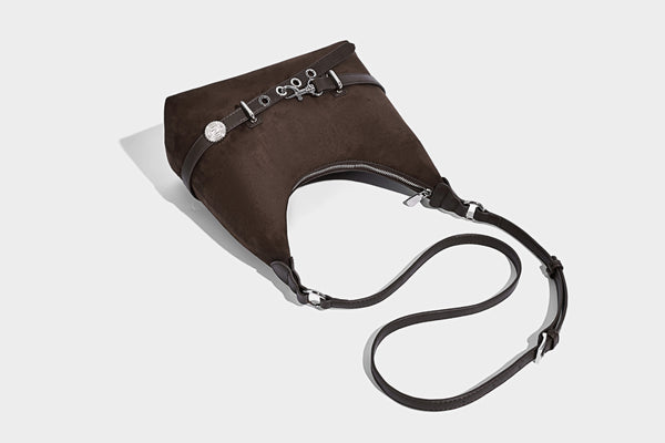 Hobo-Schultertasche in Dunkelbraun mit velourslederartiger Oberfläche, silberfarbener Gürtelschnalle und Ösenbeschlägen, verstellbarem Riemen, Detailansicht