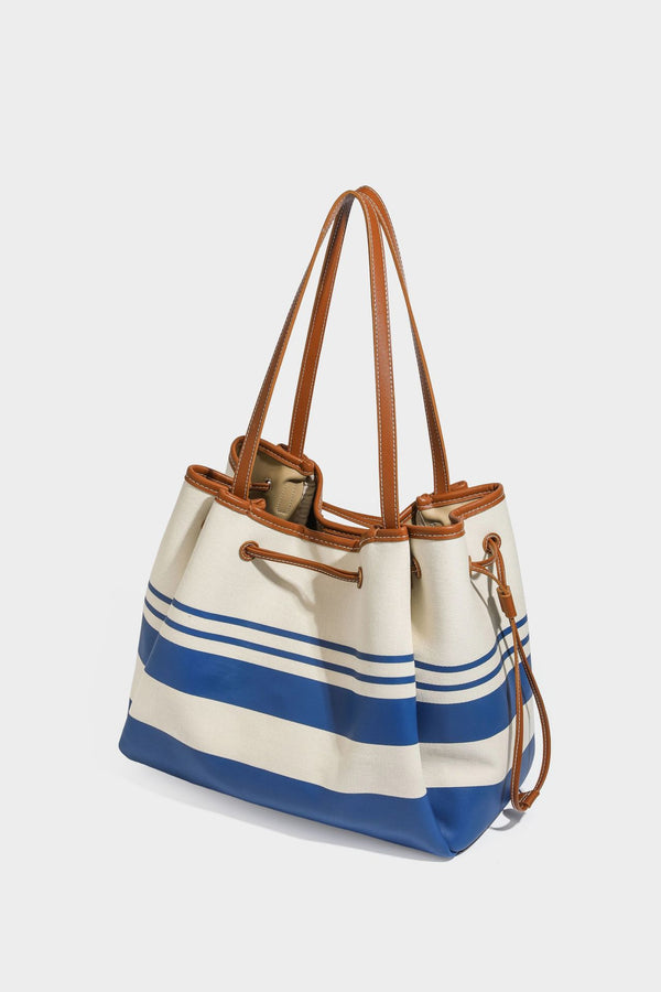 Large cream and navy striped canvas bucket tote bag with tan leather-look trim, drawstring closure, and double shoulder