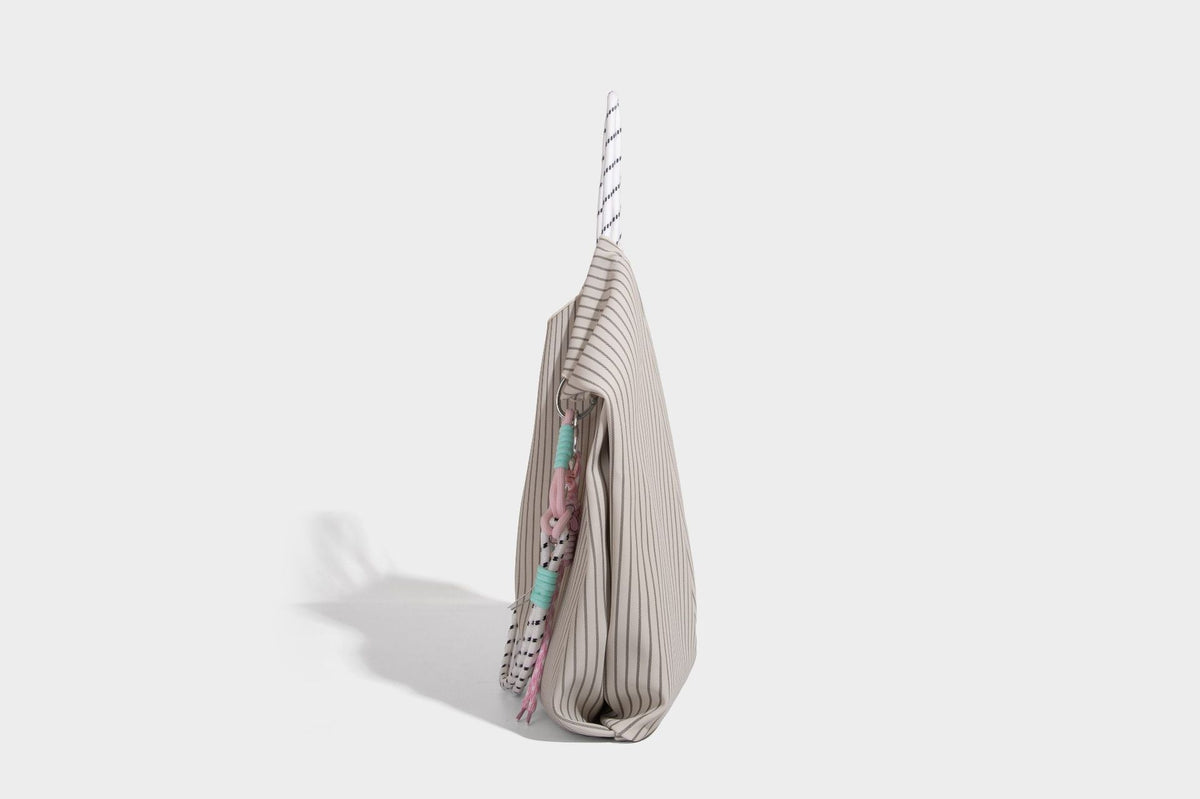Slouchy pinstripe tote bag with braided rope handles, metal ring hardware, and colorful knotted rope charm, detail view 21