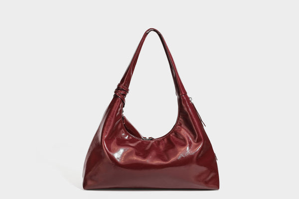 Weich fallende Hobo-Schultertasche in glänzender Lederoptik mit silberfarbenen Ösen zum Schnüren und Schleifenband auf der Vorderseite, Detailansicht