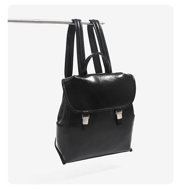 Structured glossy leather-look flap backpack handbag with dual buckle closures, top handle, and silver-tone hardware, detail
