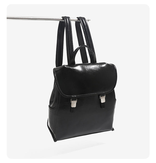 Structured glossy leather-look flap backpack handbag with dual buckle closures, top handle, and silver-tone hardware, detail