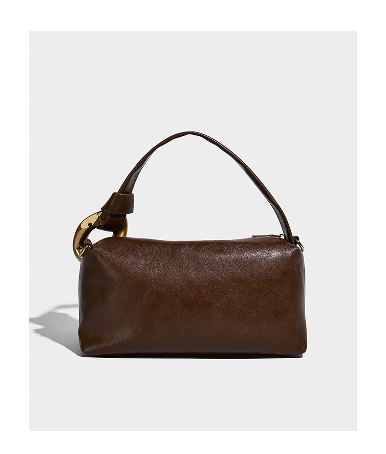 Kompakte Boston-Schultertasche in warmer Braunfarbe mit Wildlederoptik, glatten dunkelbraunen Besätzen, übergroßen goldfarbenen Ringbeschlägen und Reißverschluss oben