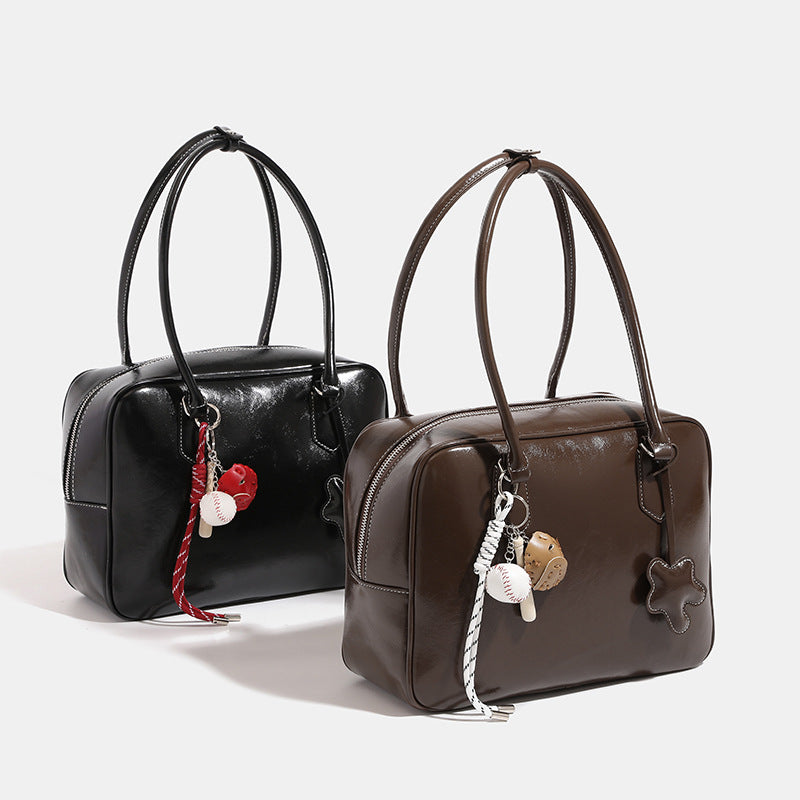 Large glossy leather-look Boston bag with double top handles, front star appliqué, and detachable baseball charm set, front